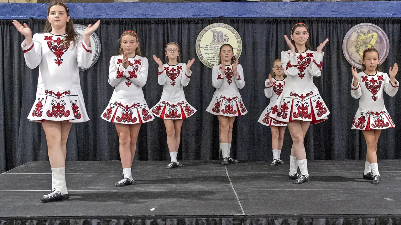 Irish dancers in red and white perform onstage