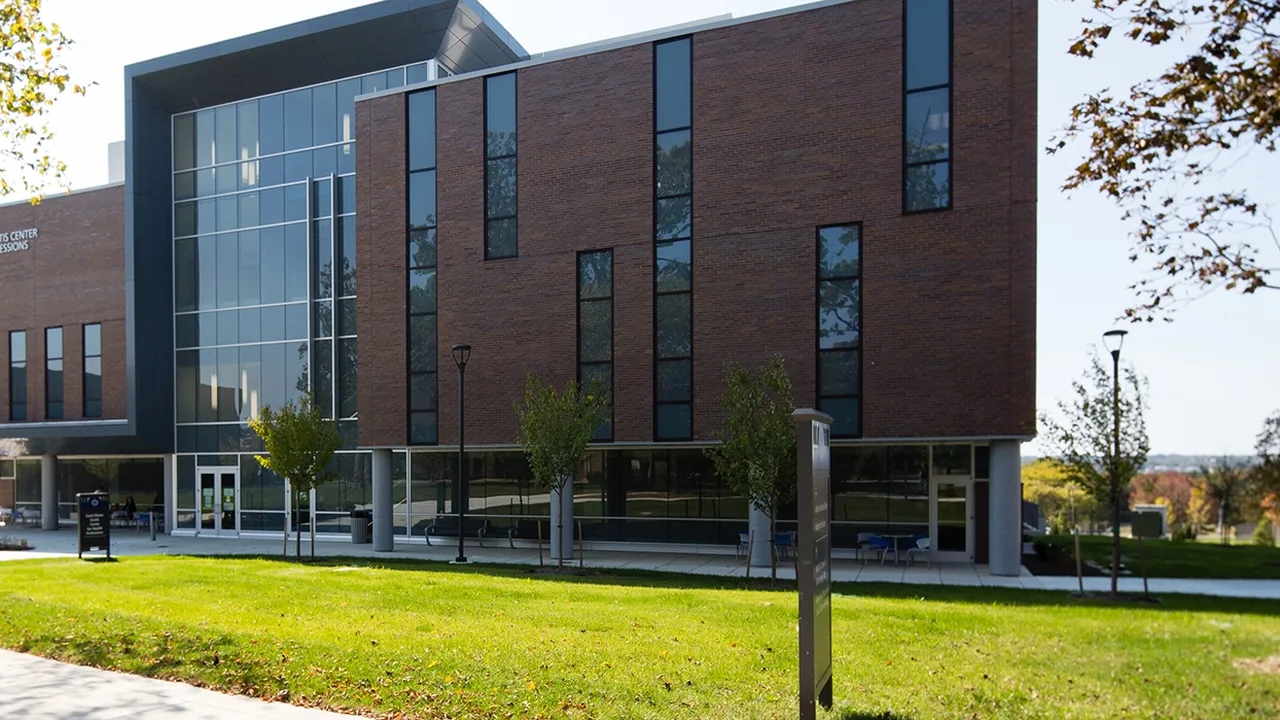 A modern brick and glass building with a green lawn in front.