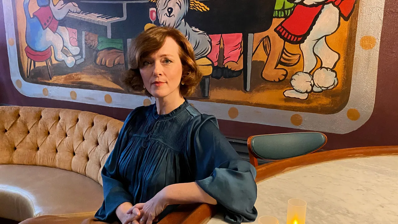 A woman in a velvet booth beneath a painted mural