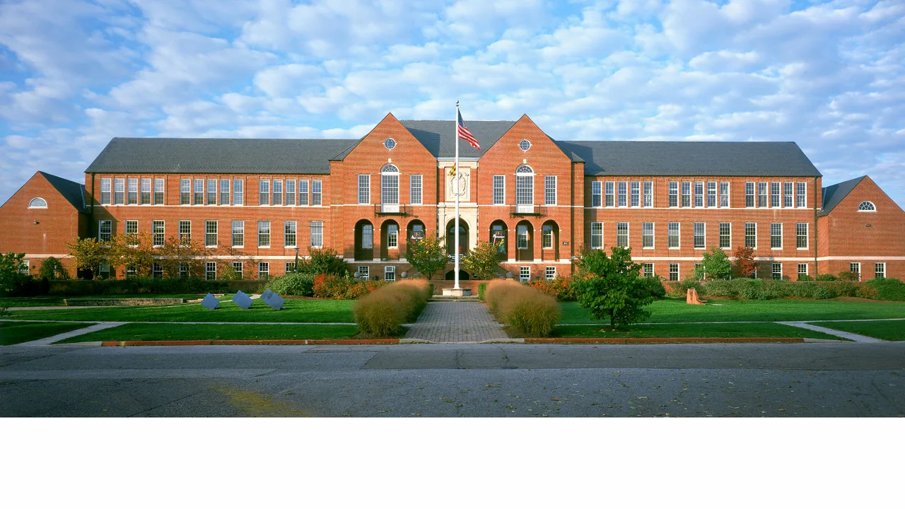 A brick campus building behind a lawn