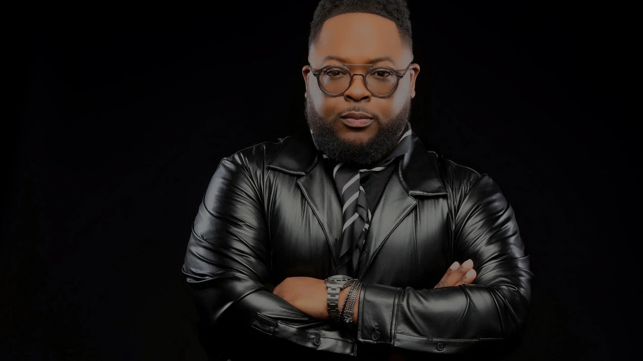 A man in a leather jacket poses with arms crossed