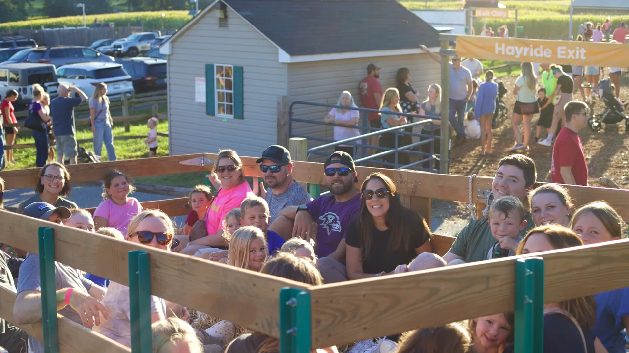 Families crowd a farm wagon on a sunny day