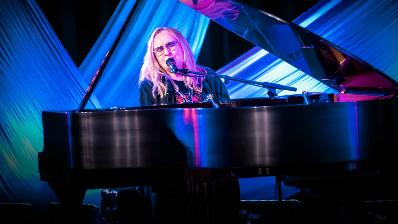 A singer plays a grand piano under blue lights