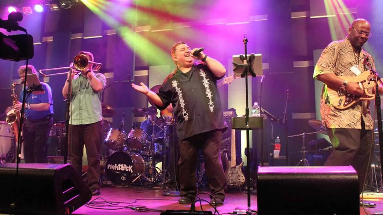 A band performs under purple stage lights