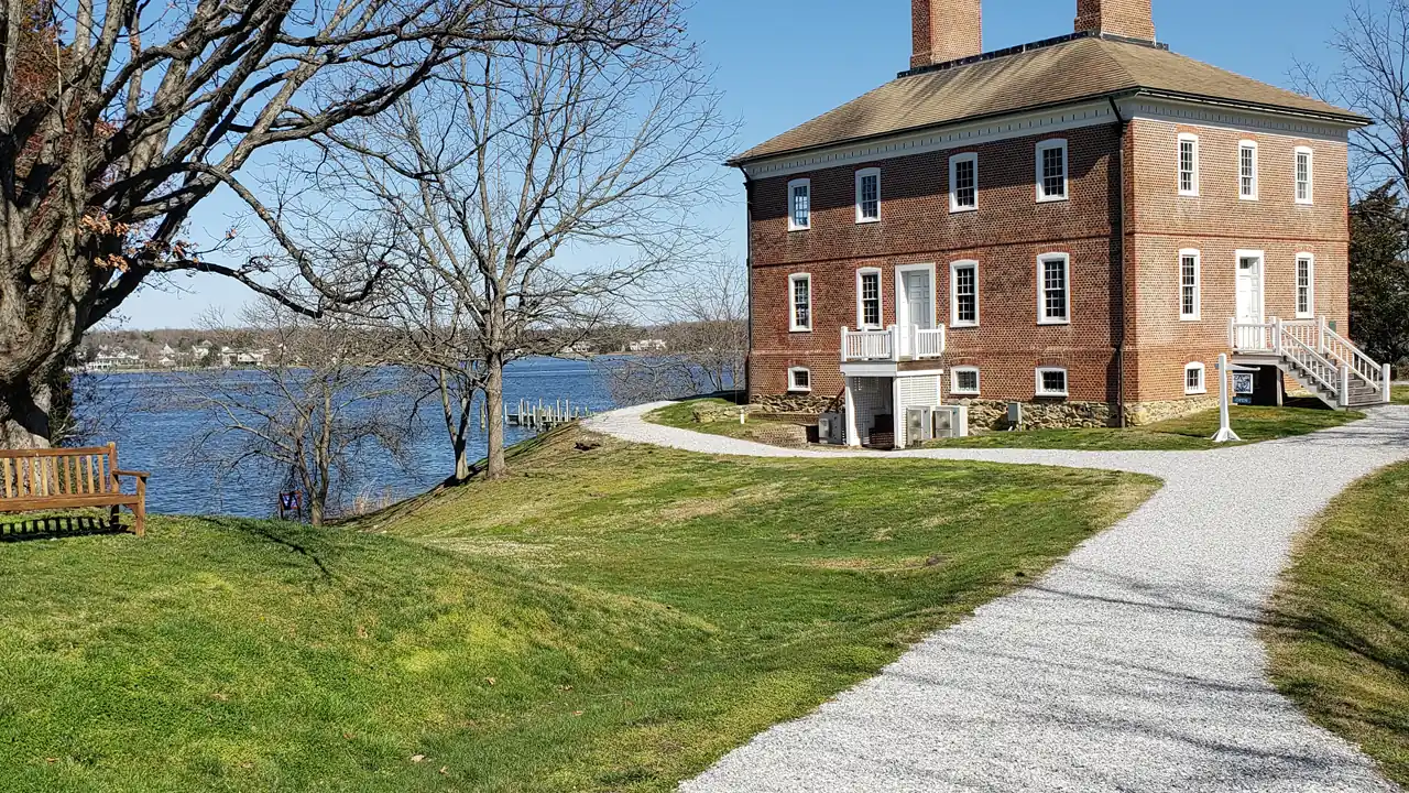 A brick colonial house on a waterfront lawn