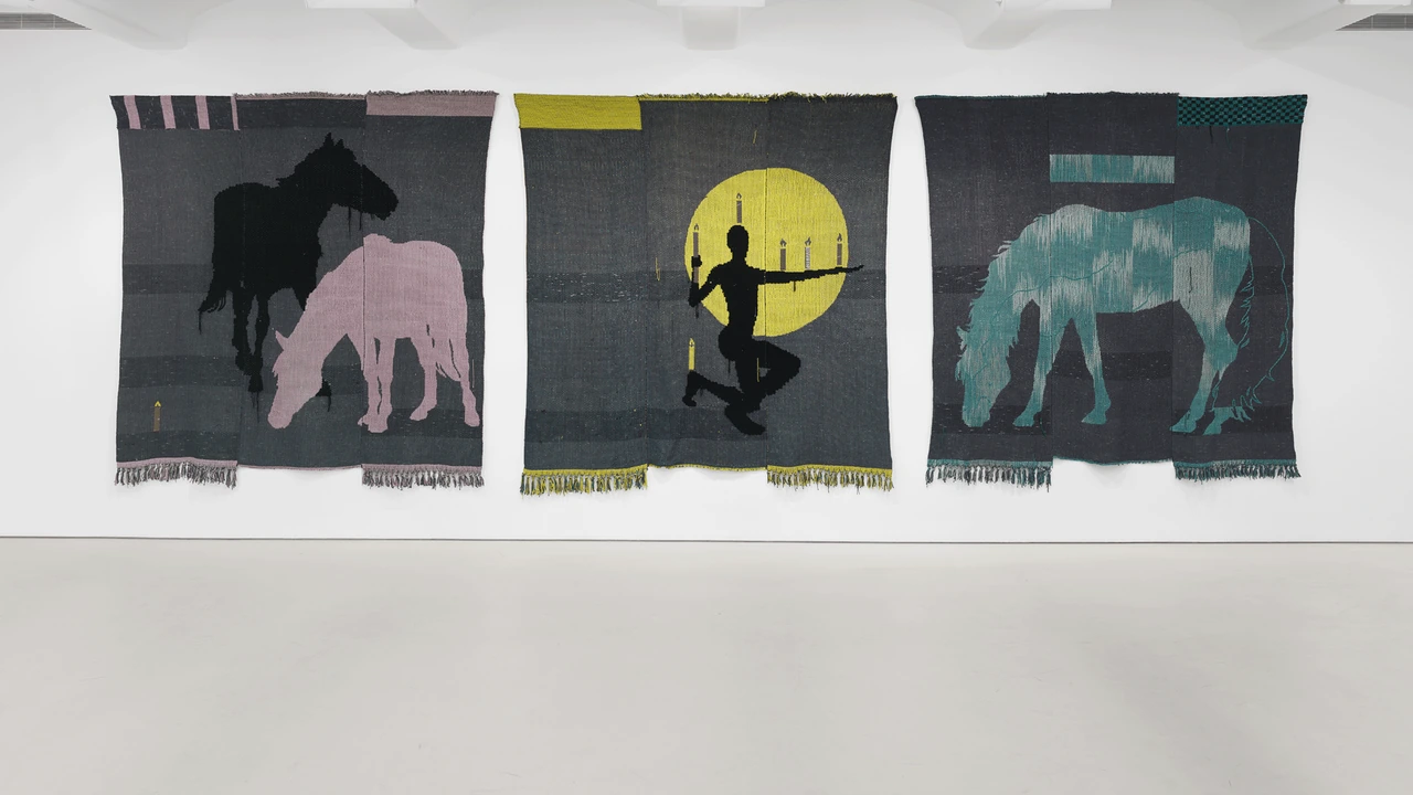Woven tapestries hang in a white gallery