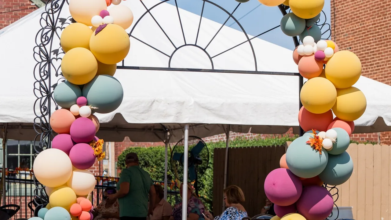 Balloon arches frame a white party tent