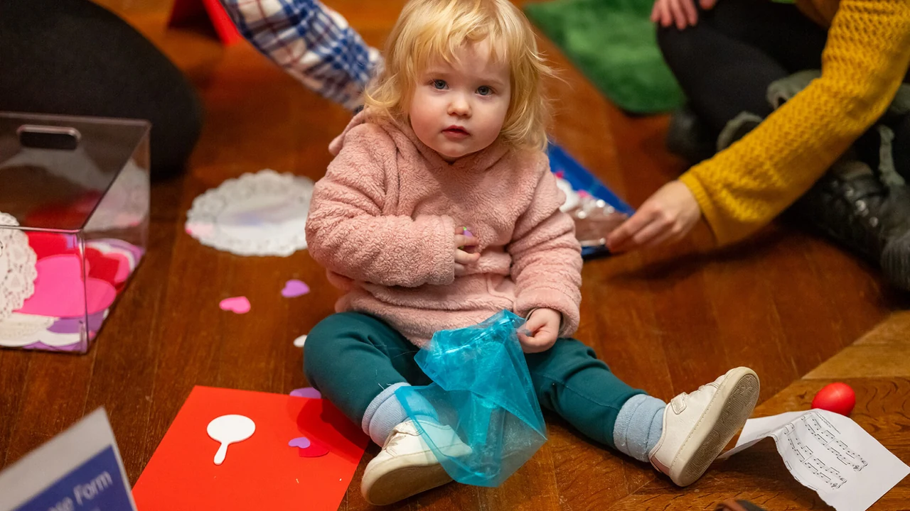 A toddler plays with craft paper on the floor