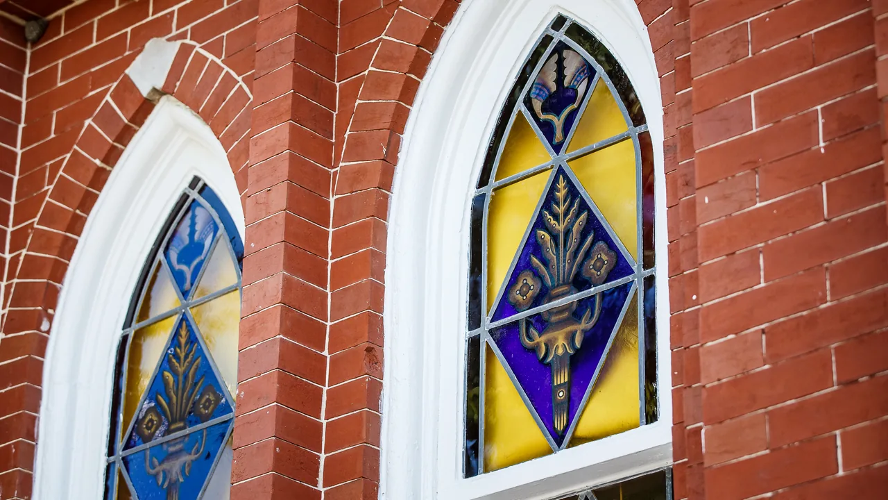 Arched stained-glass windows set in a red brick wall