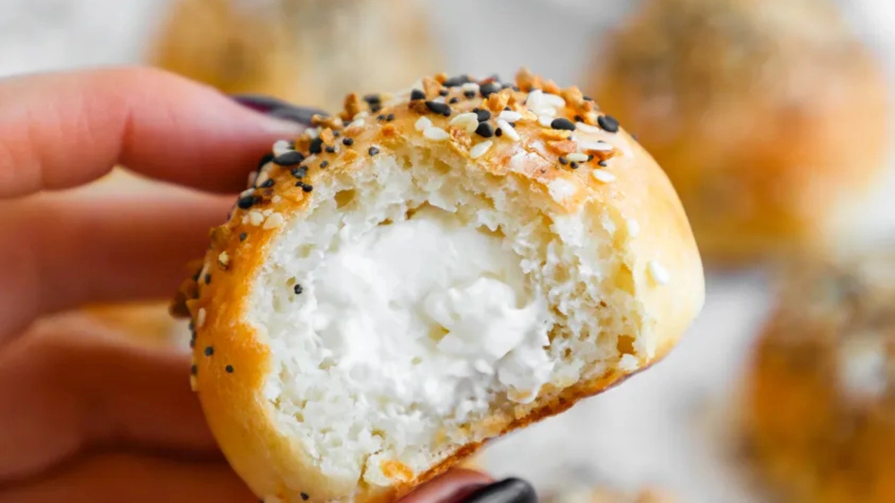 A hand holds an everything bagel