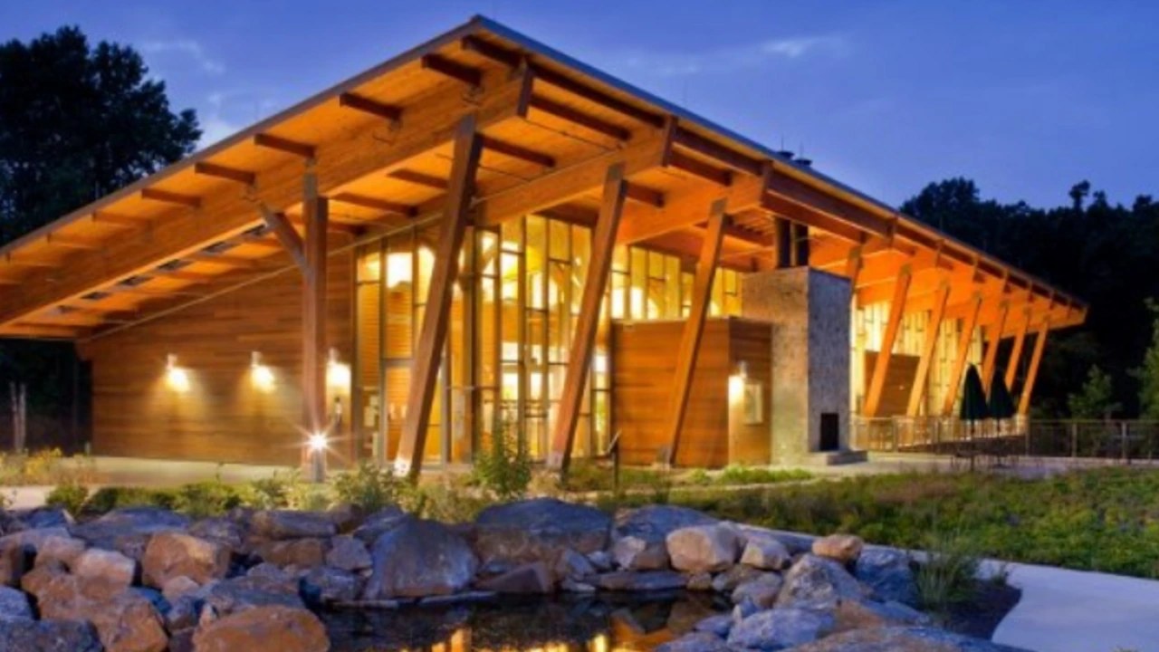 A timber pavilion lit at dusk beside a pond