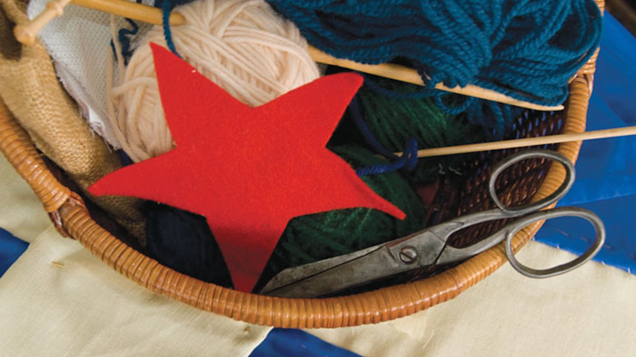 A wicker basket holds yarn, a red fabric star and scissors on a flag-patterned cloth