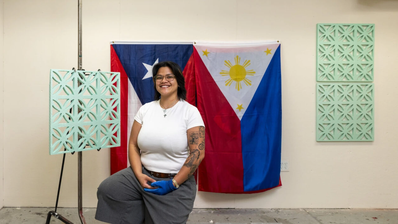 An artist sits before Puerto Rican and Philippine flags