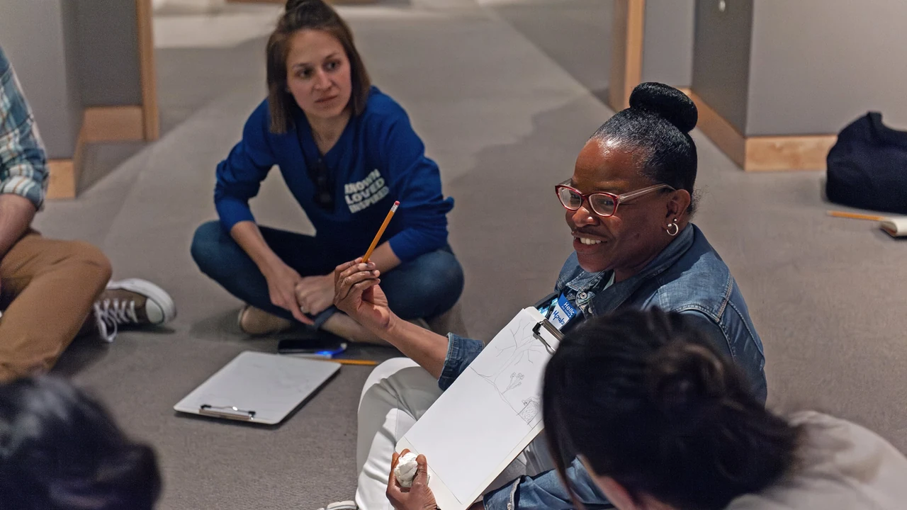 Visitors sketch together on a gallery floor