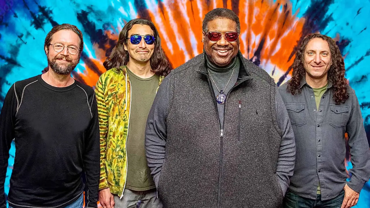 Four musicians pose against a colorful backdrop