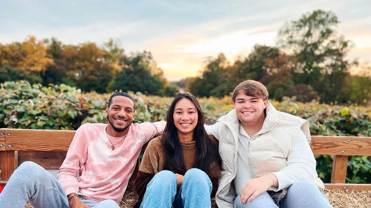 Three friends sit on a bench in a garden at sunset