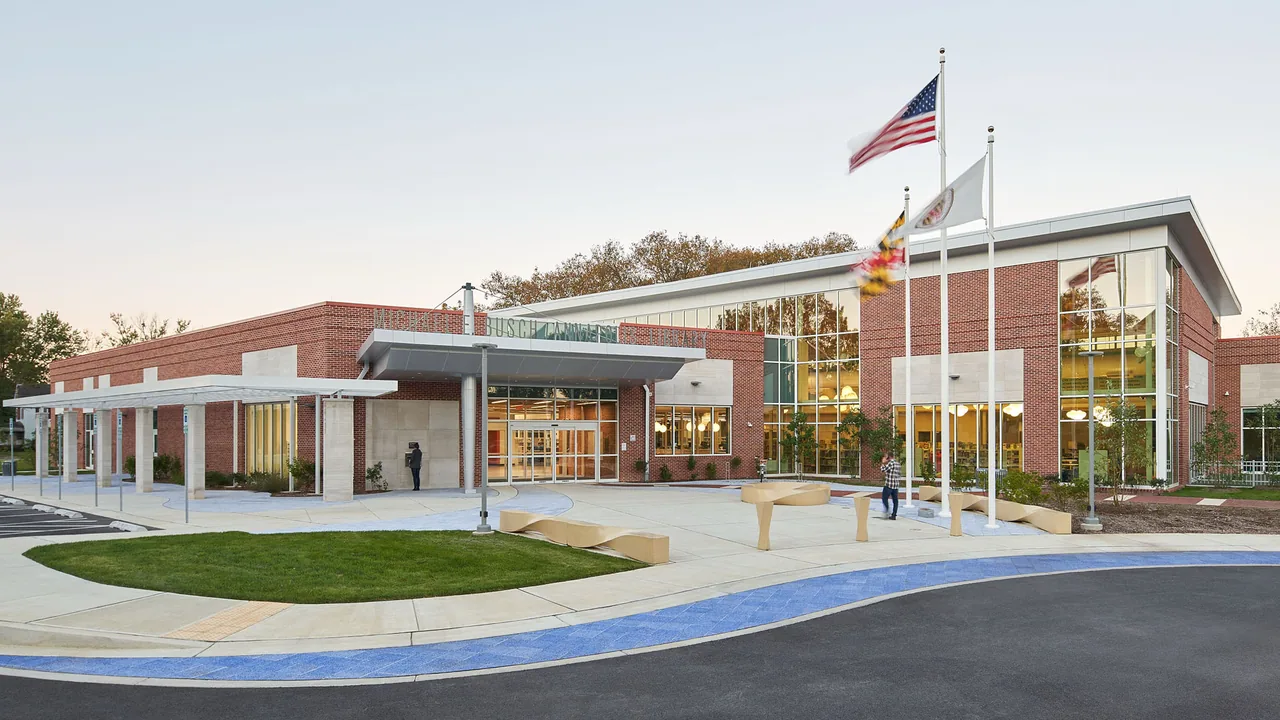 A modern brick library building with flagpoles and a landscaped entrance plaza