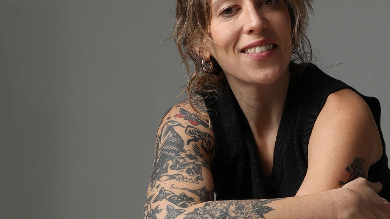 A smiling woman with tattooed arms