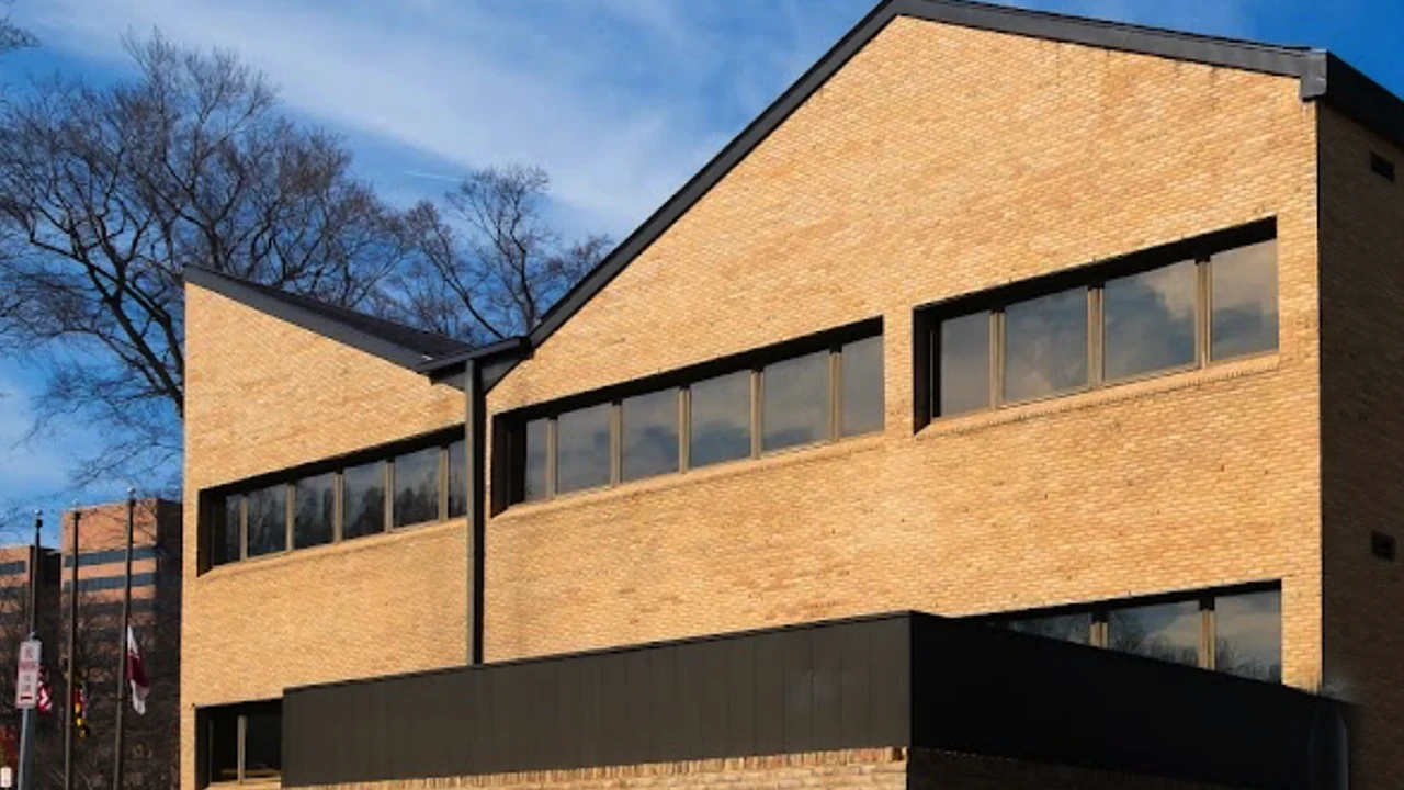 A tan brick building with tall windows under a blue sky