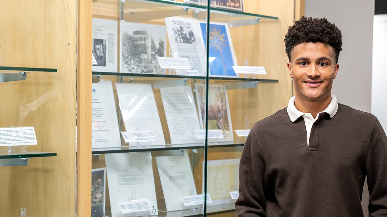 A young man stands by glass display shelves