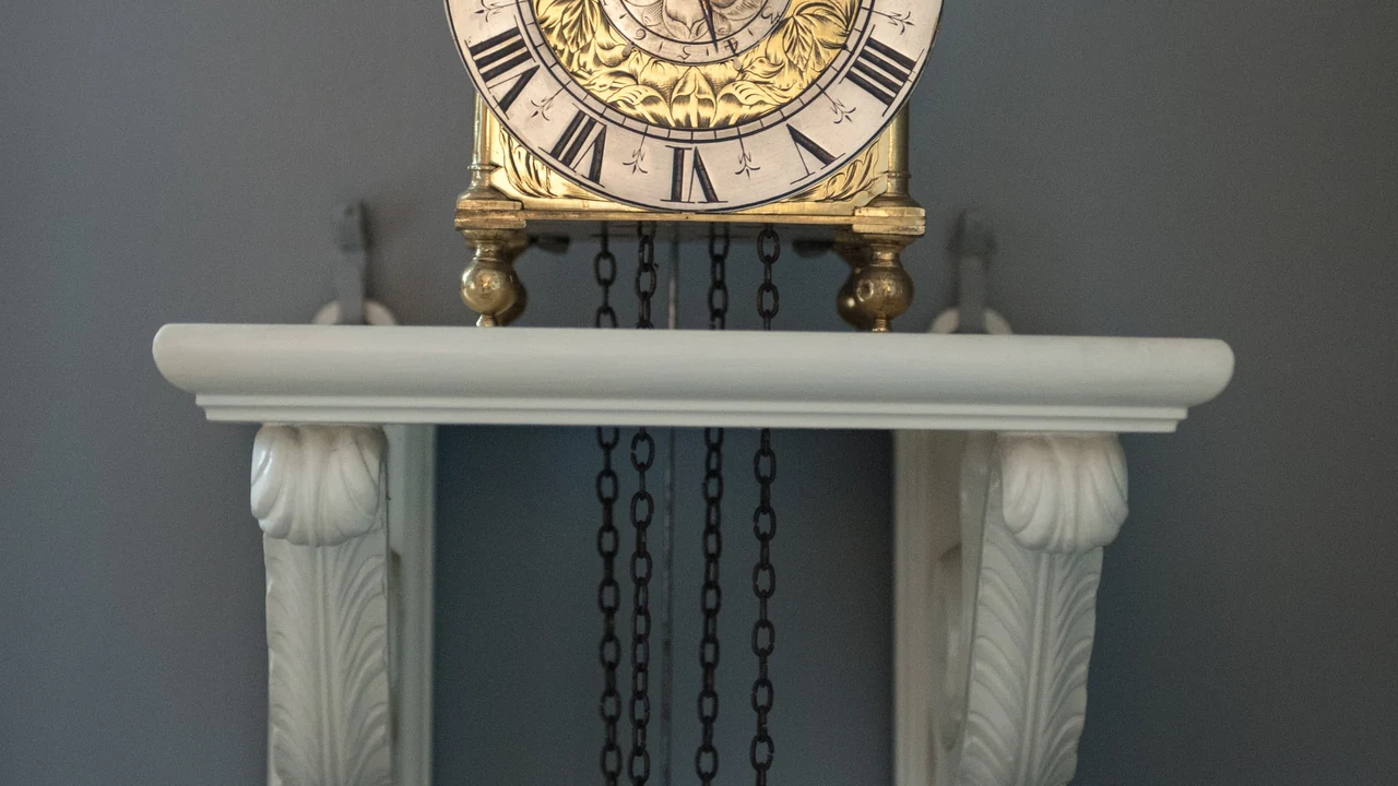 An antique clock atop a white mantel