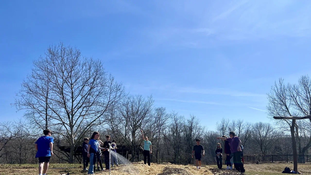 Volunteers work a farm field on a sunny day