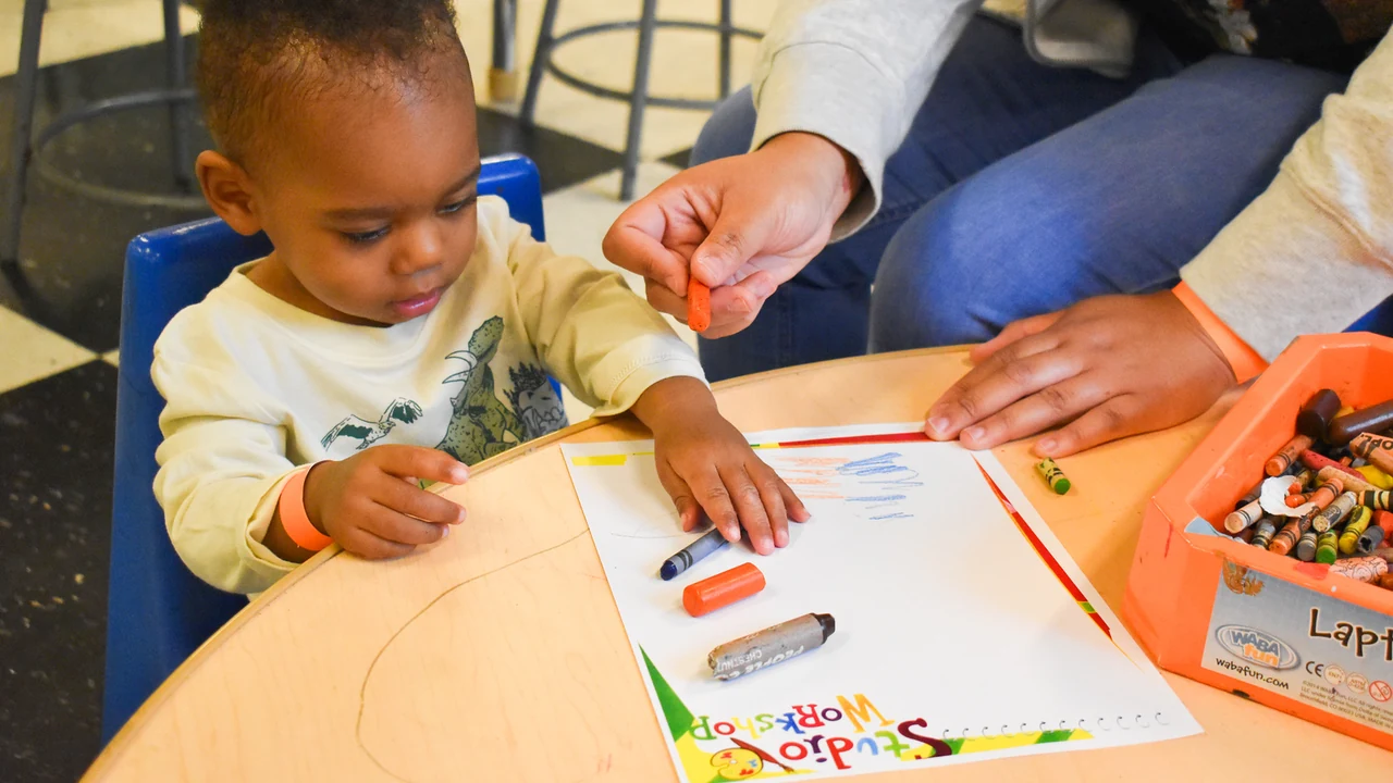 A toddler draws with markers at a table