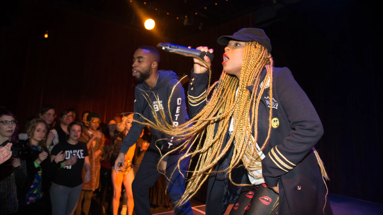 Two performers rap onstage before a crowd