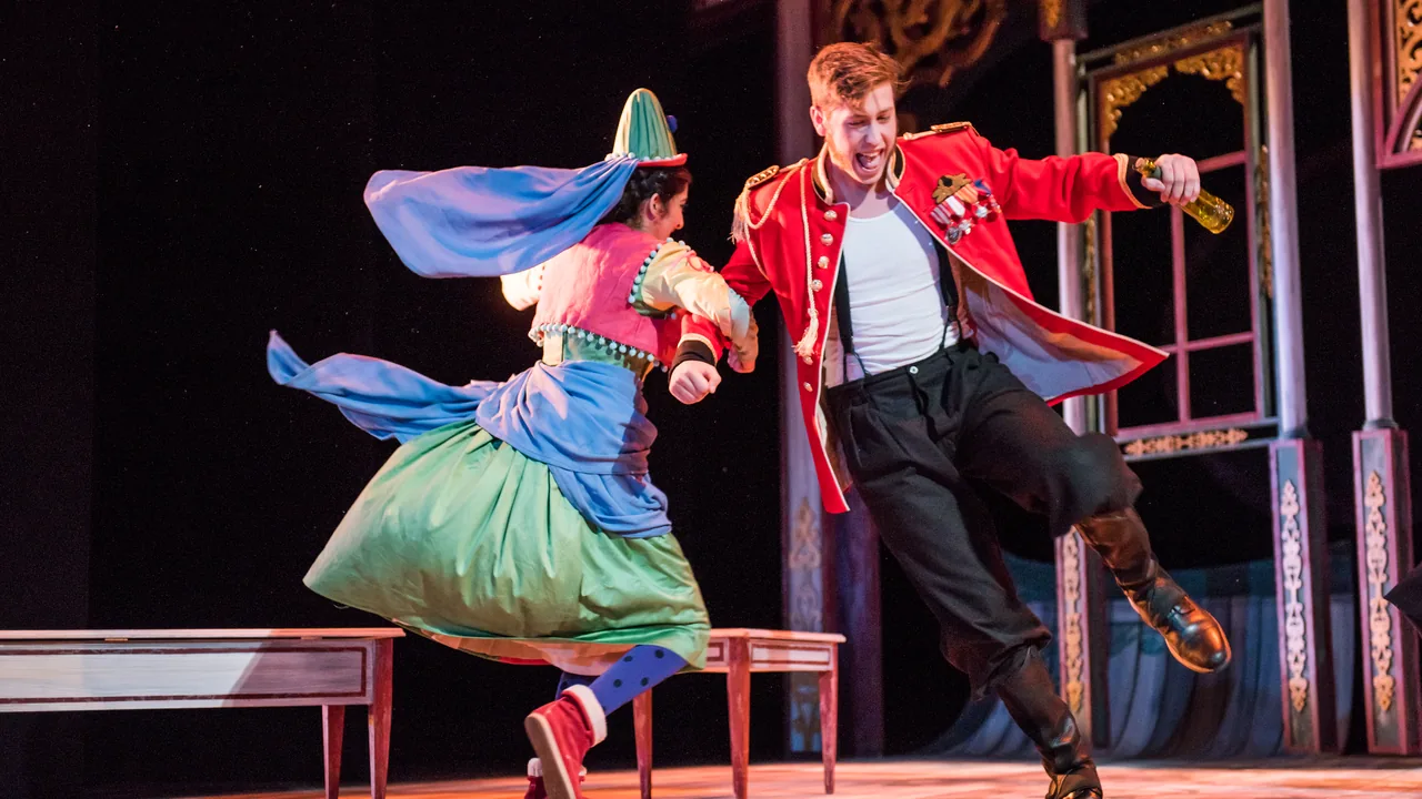 Costumed actors leap across the stage