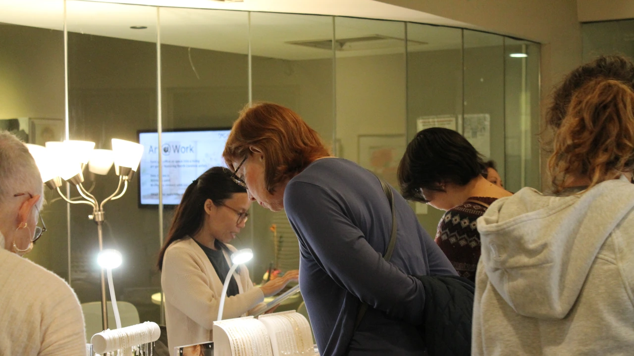 Shoppers browse among display stands in a gallery space with warm lights.