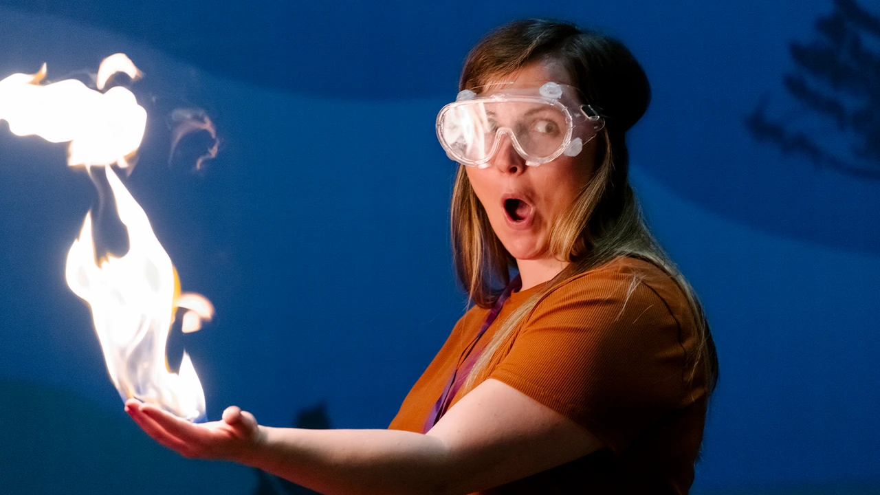 A performer holds a burst of flame in her hand