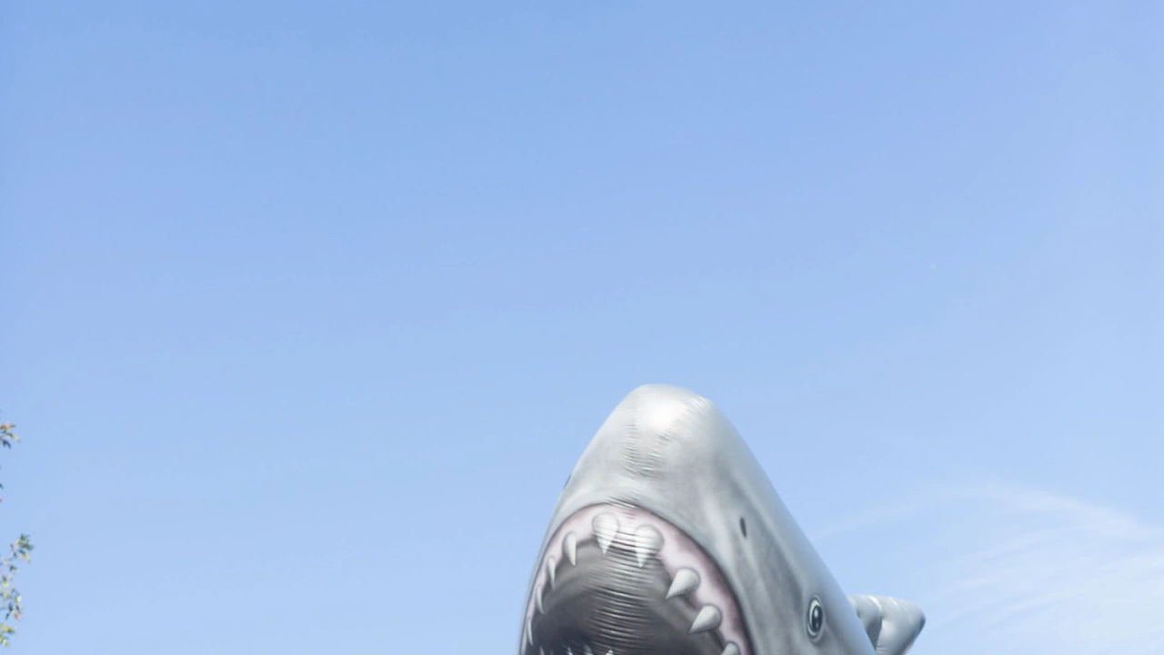 A giant shark balloon floats against a blue sky