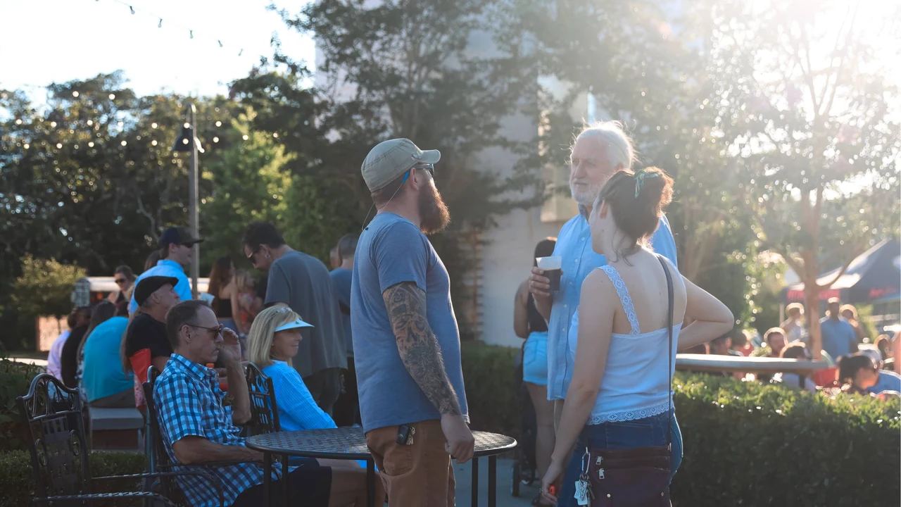 A crowd mingles outdoors on a sunny afternoon