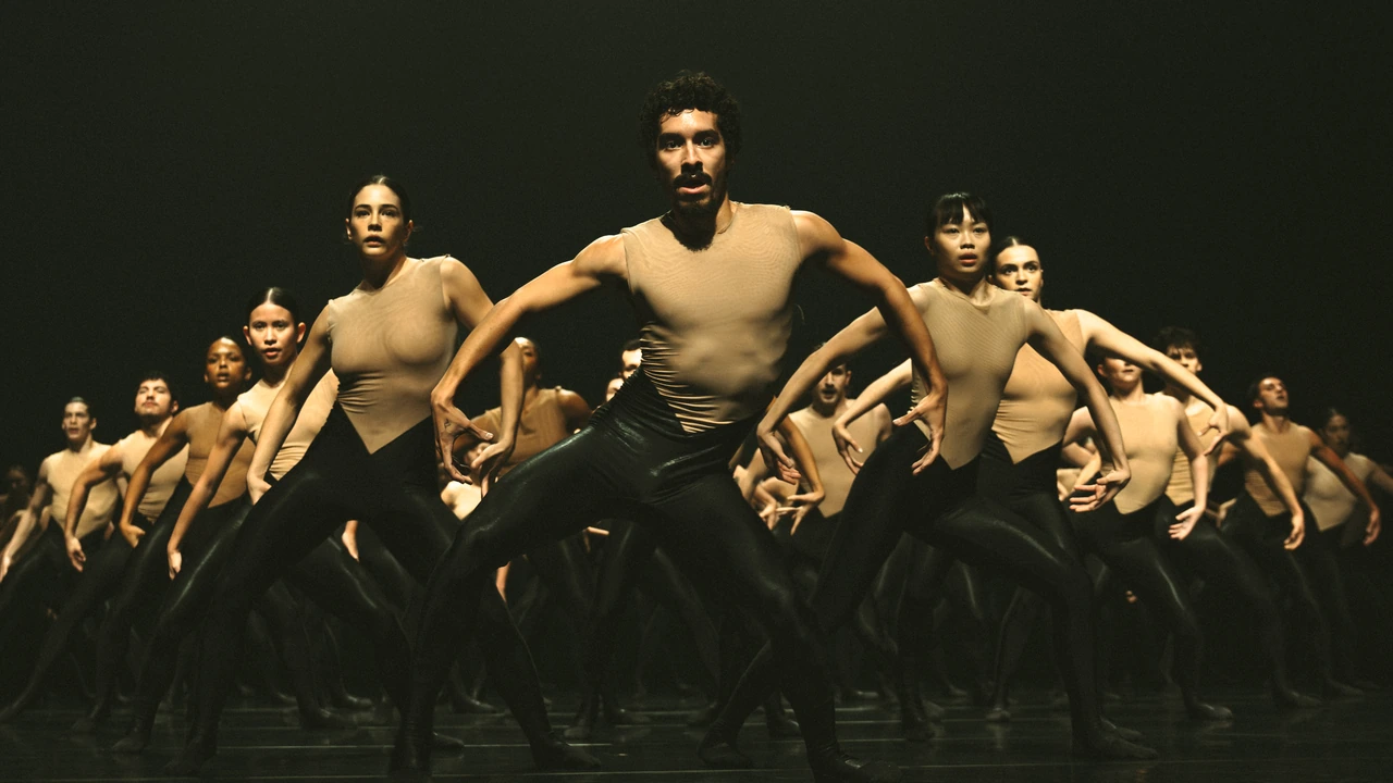 A troupe of dancers performs in dramatic light