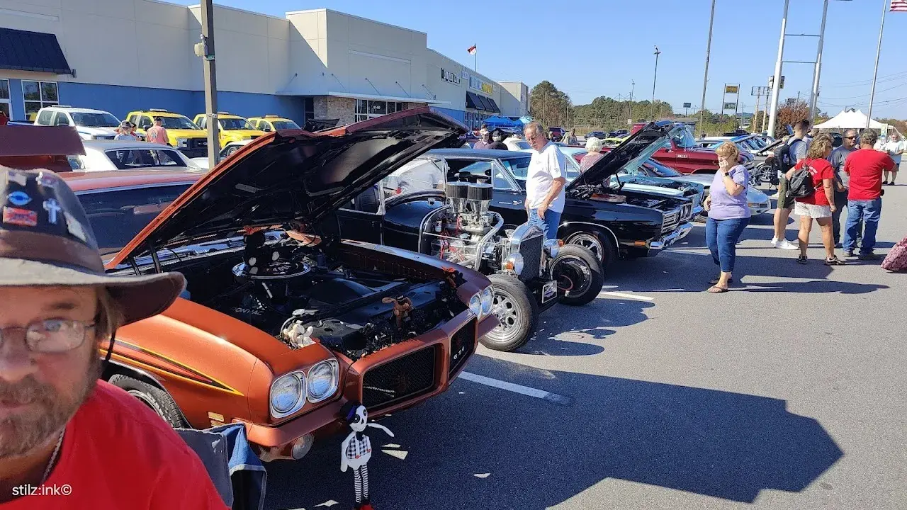 A man stands beside a classic car at a car show