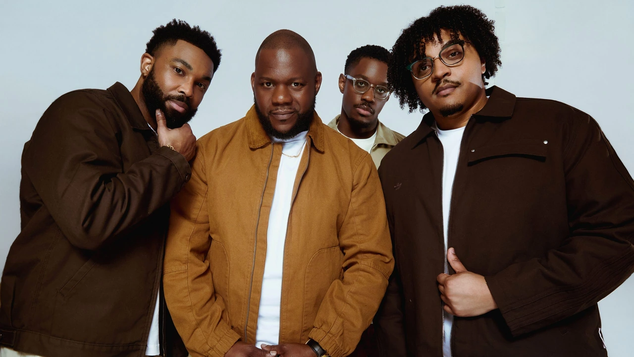 Four musicians pose in coats
