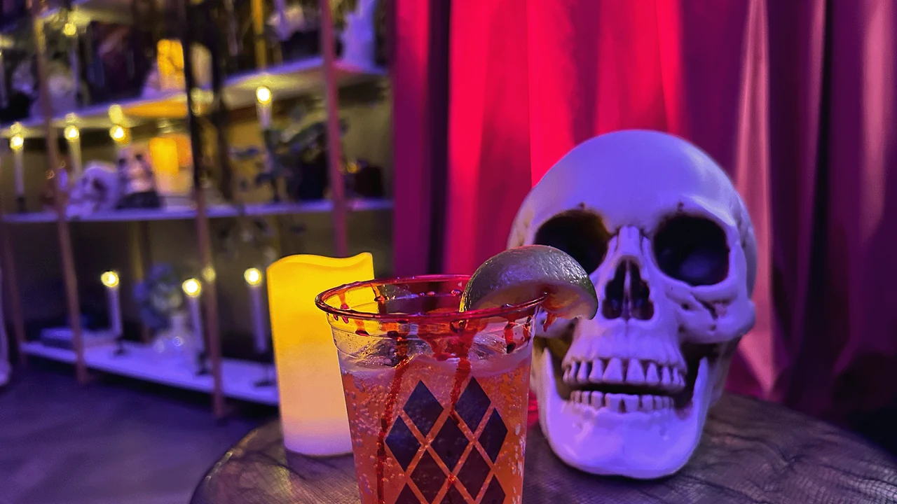A cocktail beside a skull on a candlelit bar