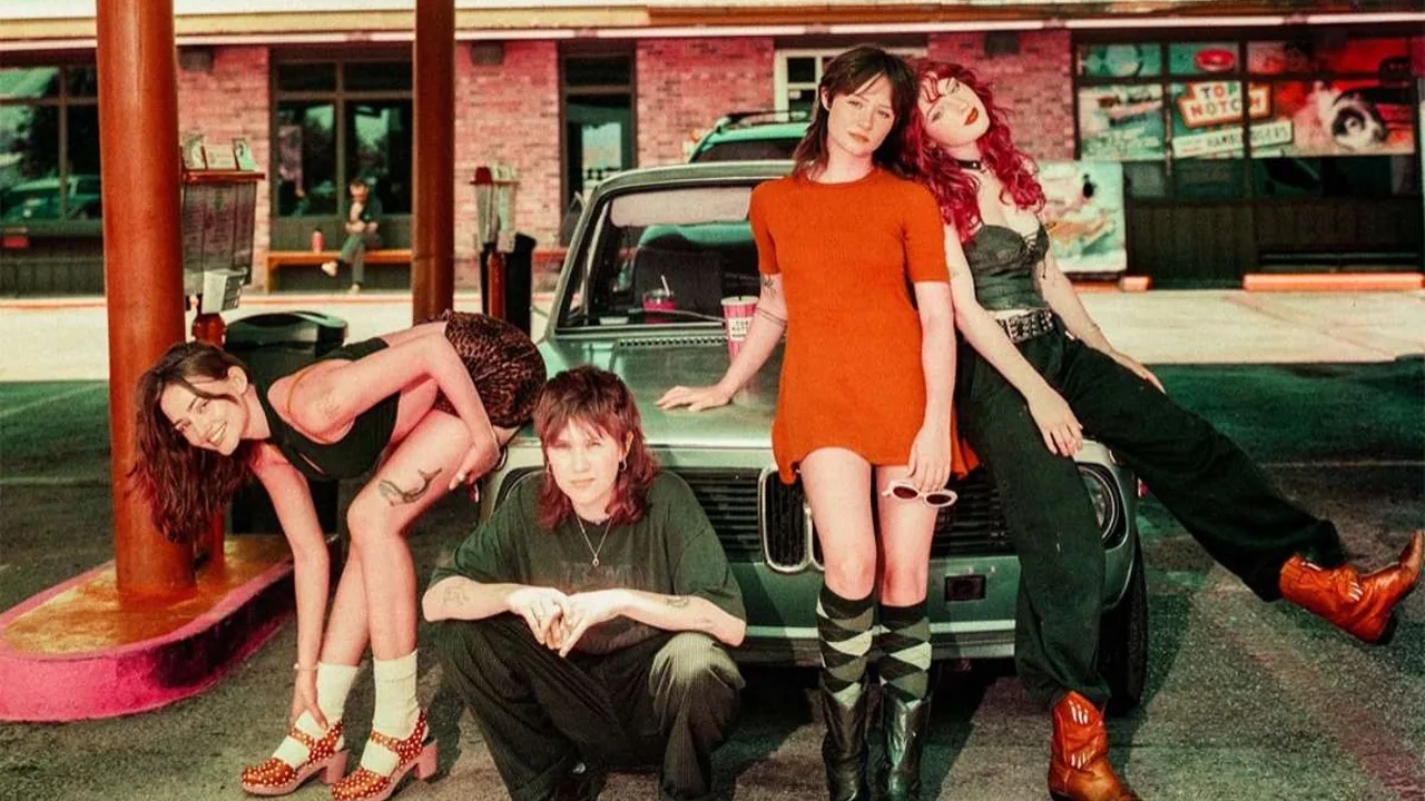 A band poses by a vintage car at a motel