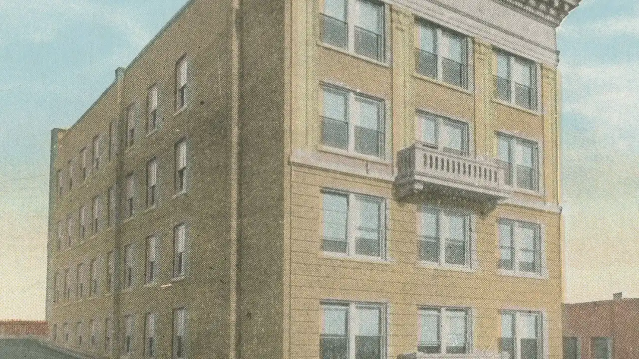 Vintage tinted image of a multistory brick building with a corner balcony.