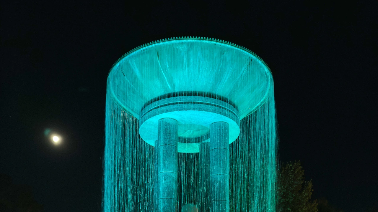 A water tower glows teal at night