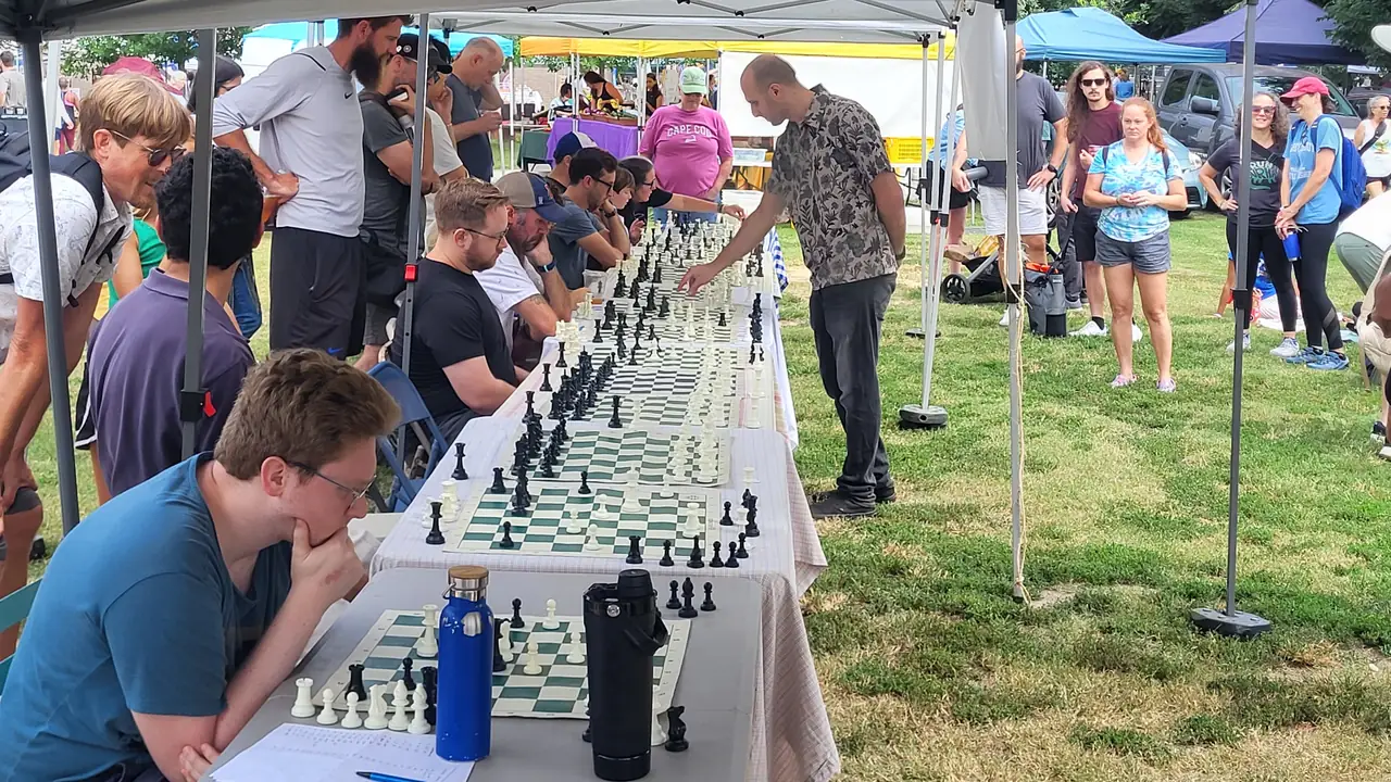 Players at rows of chess boards at an outdoor Durham Chess Club meetup