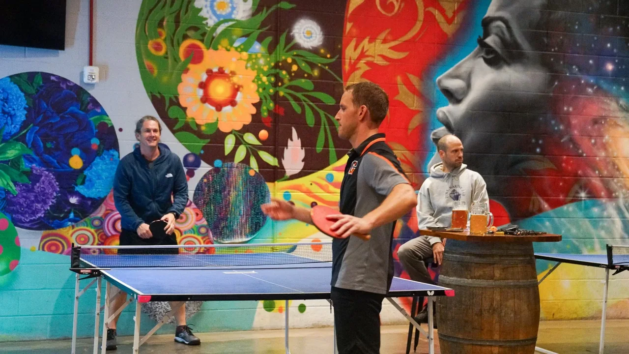 Ping-pong players in front of a mural at Hi-Wire Brewing in Durham