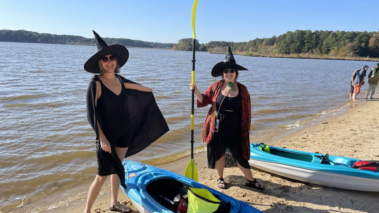 Two women in witch costumes on a lakeside beach