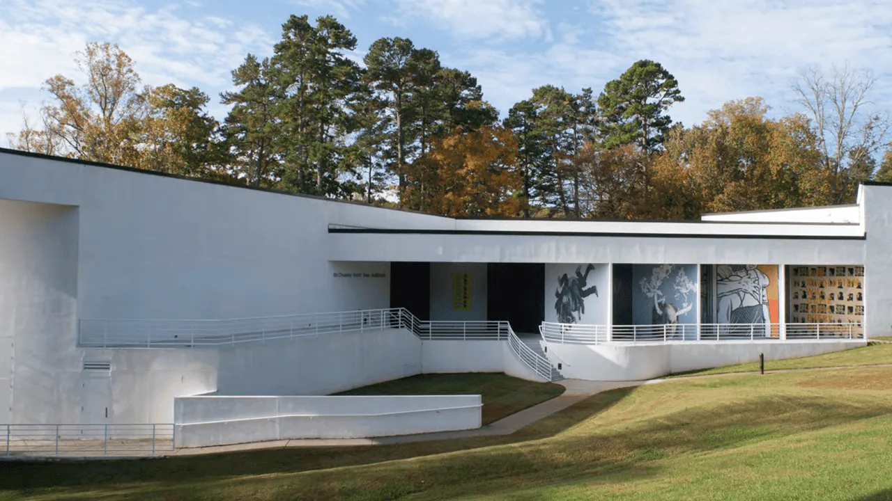 A modern white museum building among trees