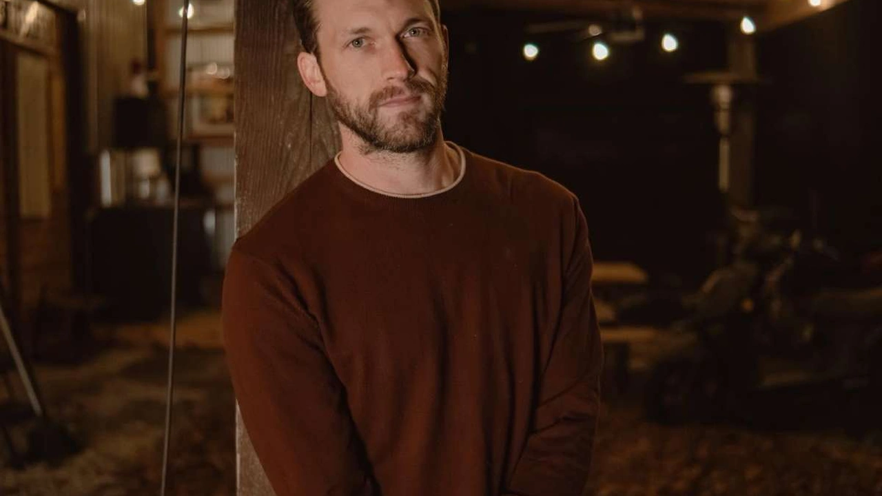 A bearded musician stands in a dim room