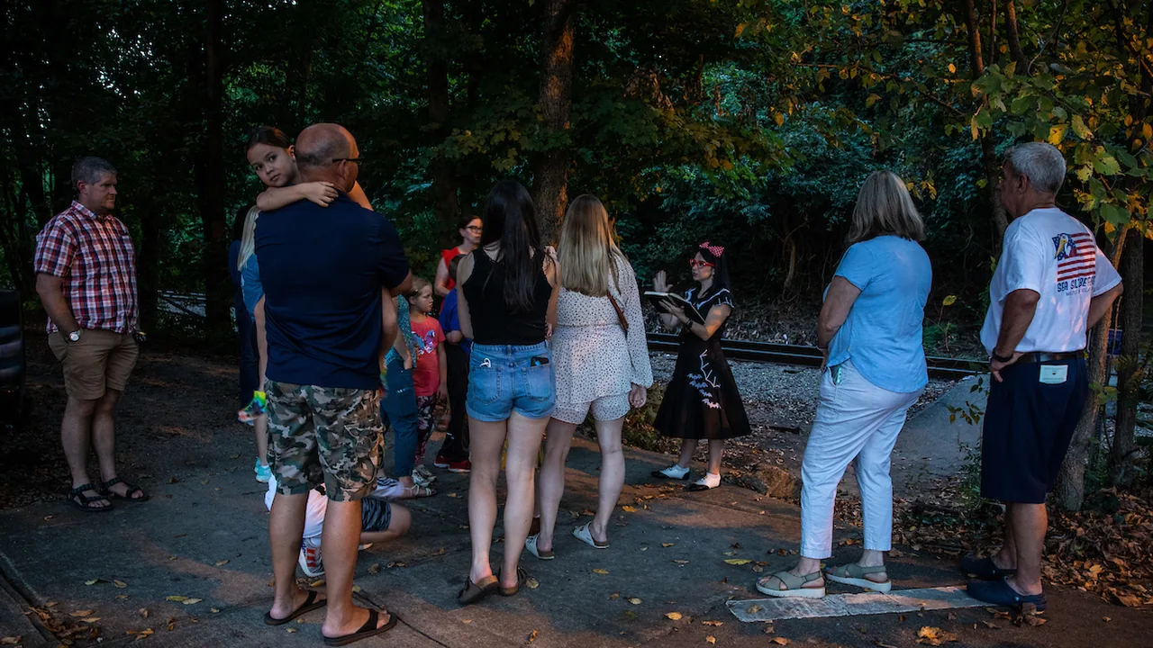 A tour group gathers in the woods at dusk