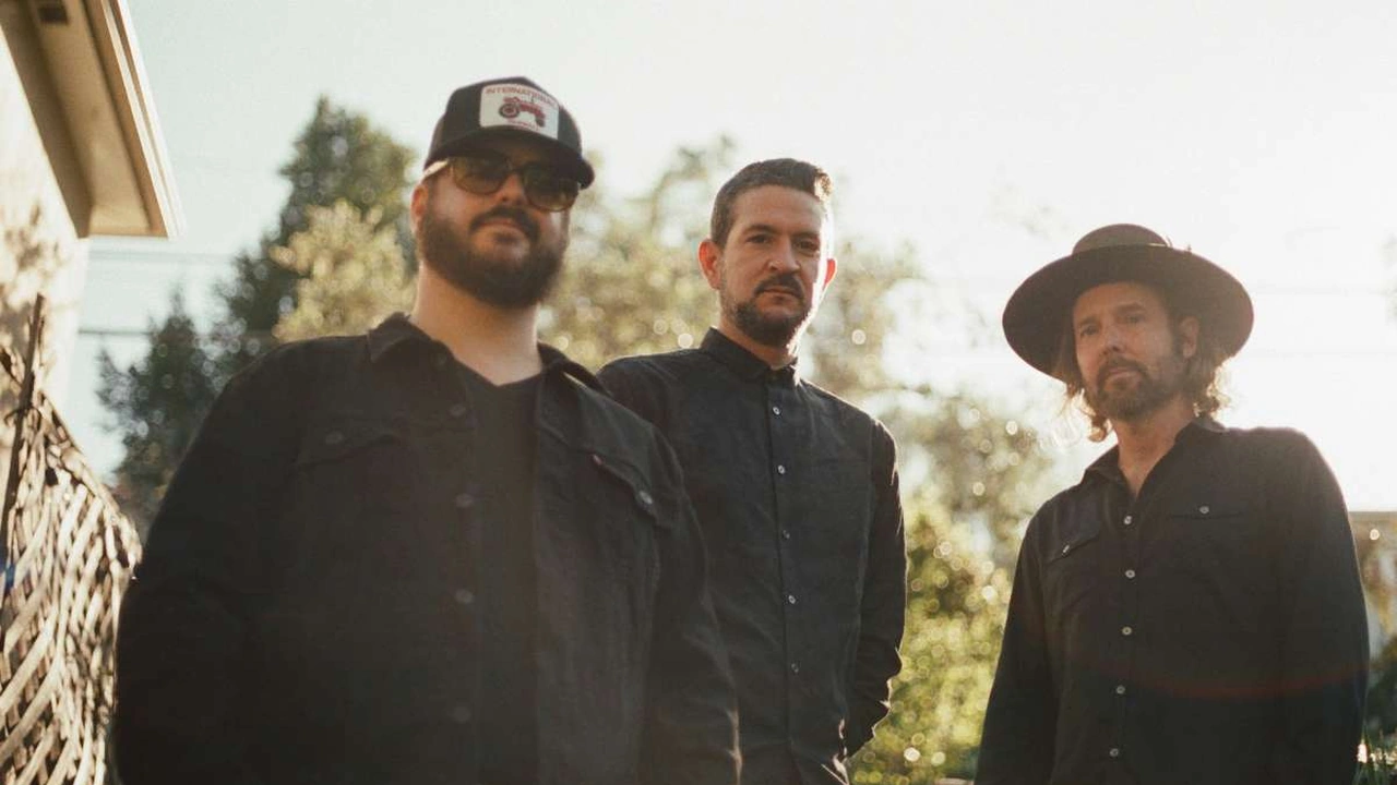 Three musicians stand in a sunny field