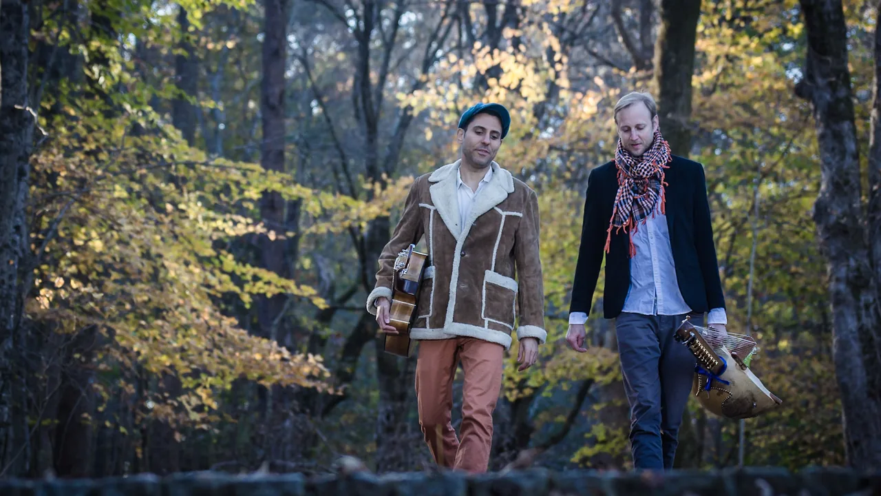 Two men walk through autumn woods