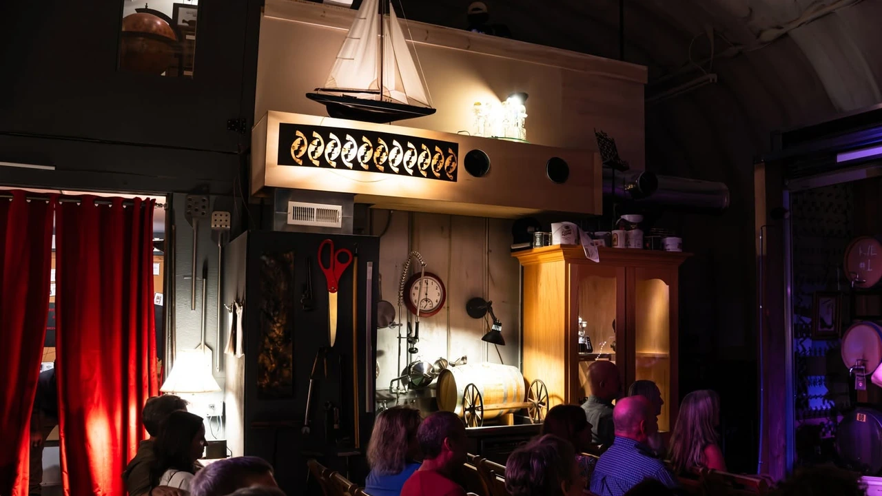 A comedy club room with a small stage and red curtains