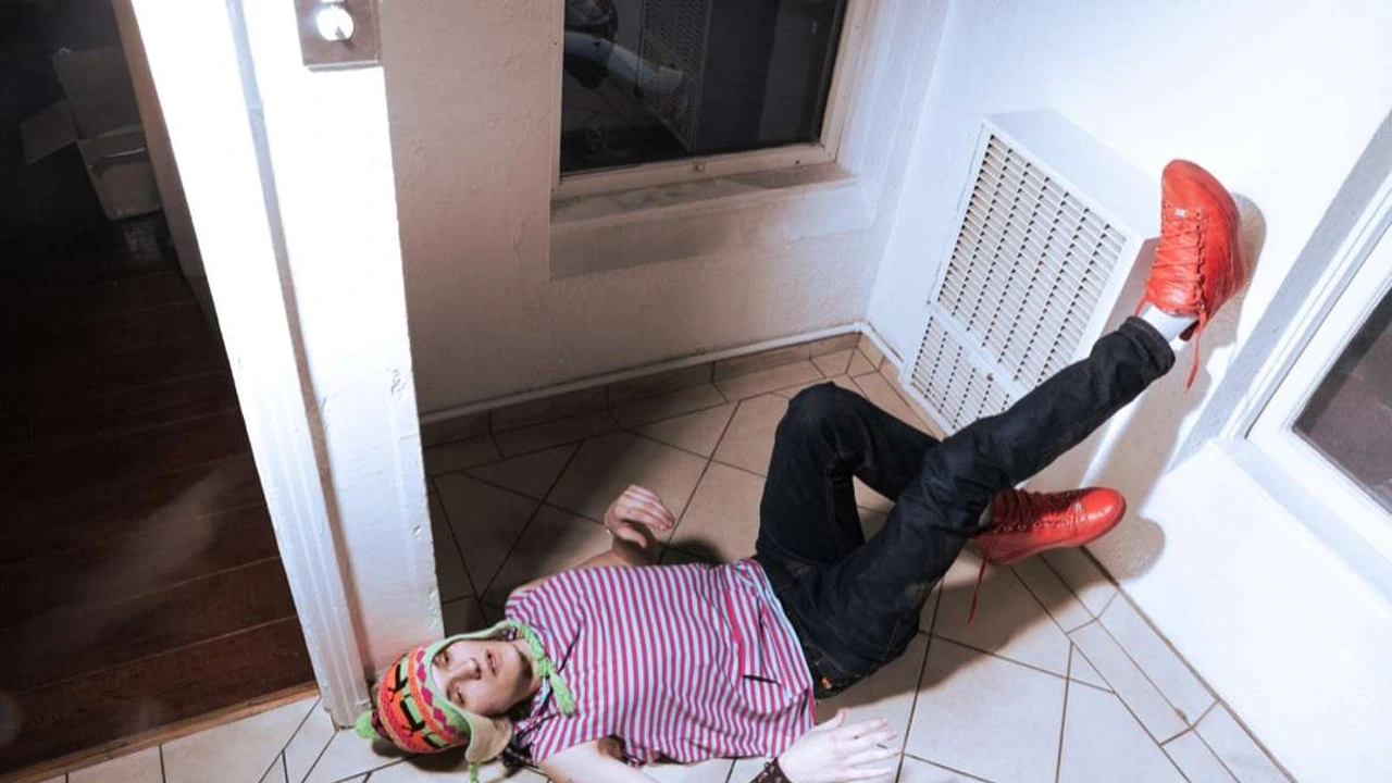 A man in a striped shirt lies on a doorway floor